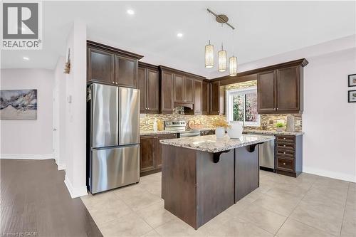 Kitchen featuring rich wood-finish cabinetry, stainless steel appliances, a central island with a light-toned countertop, a mosaic tile backsplash, and recessed lighting - 92 Desoto Drive, Hamilton, ON - Indoor Photo Showing Kitchen With Upgraded Kitchen