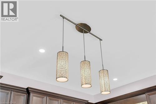 Linear pendant light fixture featuring three cylindrical shades with a patterned design, complemented by recessed ceiling lights and dark wood cabinetry - 92 Desoto Drive, Hamilton, ON - Indoor Photo Showing Other Room