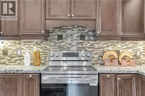 Gourmet kitchen featuring a stainless steel range, mottled tile backsplash, wood cabinetry, under-cabinet lighting, and speckled countertops - 92 Desoto Drive, Hamilton, ON - Indoor Photo Showing Kitchen With Upgraded Kitchen