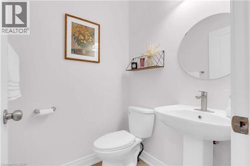 Pedestal sink with a contemporary faucet and circular mirror - 92 Desoto Drive, Hamilton, ON - Indoor Photo Showing Bathroom