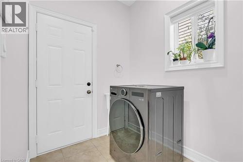 Bright utility area featuring a window, white paneled door, and neutral tile flooring - 92 Desoto Drive, Hamilton, ON - Indoor Photo Showing Laundry Room