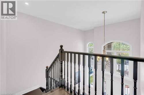 Staircase featuring dark wood newel posts and balusters, a recessed ceiling light, and arched windows - 92 Desoto Drive, Hamilton, ON - Indoor Photo Showing Other Room