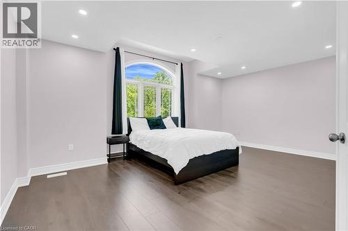 Bedroom featuring a large arched window, dark wood-finish flooring, recessed lighting, white baseboards, and a white interior door with dark hardware - 92 Desoto Drive, Hamilton, ON - Indoor Photo Showing Bedroom