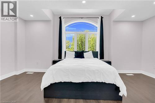 Arched window with exterior tree scenery, wood-finish flooring, recessed lighting, and white baseboards - 92 Desoto Drive, Hamilton, ON - Indoor Photo Showing Bedroom