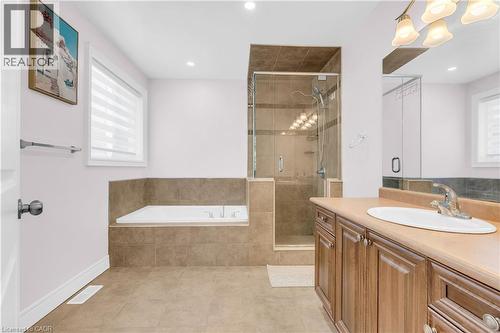 Bathroom featuring a built-in soaking tub, glass-enclosed shower, single vanity with wood cabinetry, and neutral tile flooring - 92 Desoto Drive, Hamilton, ON - Indoor Photo Showing Bathroom