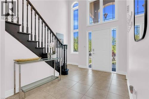 Foyer featuring a dark wood-finish staircase with turned balusters, a white entry door with clear glass sidelights, and overhead transom windows - 92 Desoto Drive, Hamilton, ON - Indoor Photo Showing Other Room
