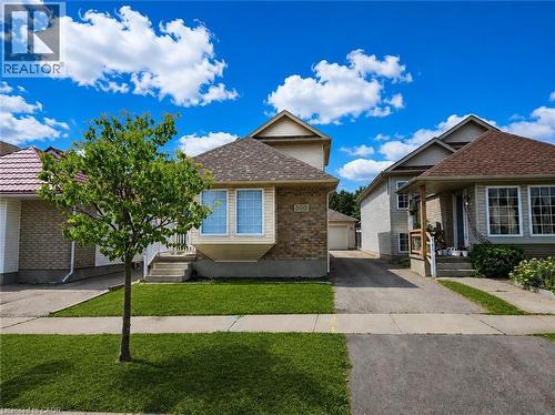 Traditional-style residence featuring a brick and siding facade, a bay window, a shingled roof, a concrete walkway, and a manicured front lawn - 390 Wake Robin Crescent, Kitchener, ON - Outdoor With Facade