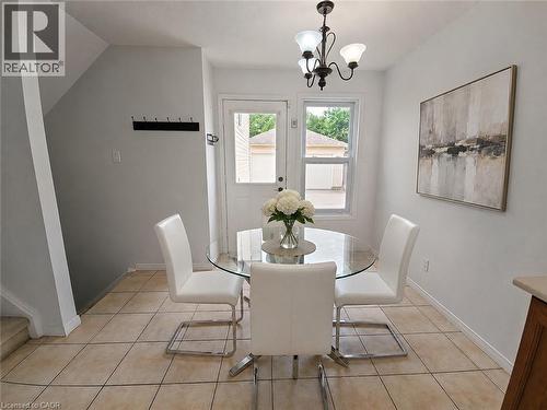 Tiled flooring throughout, featuring a glass-paneled door, a window with exterior views, and a three-light chandelier - 390 Wake Robin Crescent, Kitchener, ON - Indoor Photo Showing Dining Room