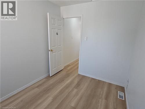 Light wood-finish flooring complements the neutral wall color - 390 Wake Robin Crescent, Kitchener, ON - Indoor Photo Showing Other Room
