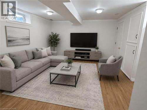 Spacious room featuring wood-finish flooring, recessed window, ceiling-mounted lighting, built-in cabinetry, and crown molding - 390 Wake Robin Crescent, Kitchener, ON - Indoor Photo Showing Living Room