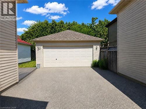 Detached garage with a paneled door, shingled roof, and exterior wall sconces - 390 Wake Robin Crescent, Kitchener, ON - Outdoor With Exterior