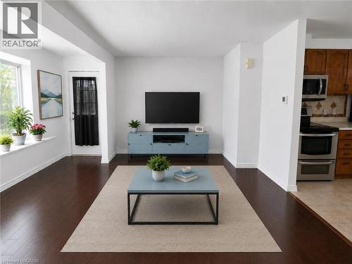 Bright living area featuring dark wood-finish flooring, white baseboards, and a large window with a deep sill - 390 Wake Robin Crescent, Kitchener, ON - Indoor Photo Showing Living Room