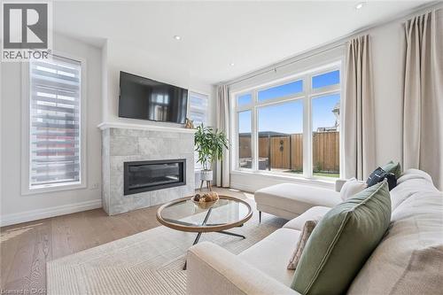 Living area featuring a tiled fireplace with an insert, a large picture window, recessed lighting, and wood-finish flooring - 30 Waterbow Trail, Kitchener, ON - Indoor Photo Showing Living Room With Fireplace