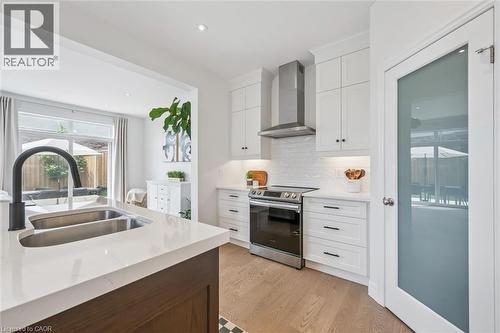 Bright kitchen featuring white shaker cabinetry, stainless steel appliances, a white subway tile backsplash, and light wood-finish flooring - 30 Waterbow Trail, Kitchener, ON - Indoor Photo Showing Kitchen With Double Sink With Upgraded Kitchen