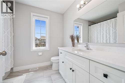 Bathroom featuring a white vanity with black hardware, a polished chrome faucet, a large wall-mounted mirror, and a window with white trim - 30 Waterbow Trail, Kitchener, ON - Indoor Photo Showing Bathroom