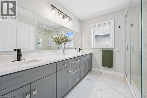 Contemporary bathroom featuring a dual vanity with light gray cabinetry, white countertops, and matte black fixtures - 30 Waterbow Trail, Kitchener, ON - Indoor Photo Showing Bathroom