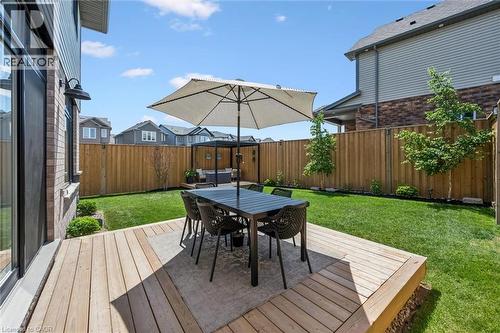 Expansive backyard featuring a large wood deck, manicured lawn, and privacy fencing - 30 Waterbow Trail, Kitchener, ON - Outdoor With Deck Patio Veranda