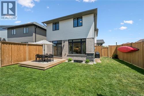 Modern rear exterior featuring a raised wooden deck, full-height windows, a full-lite glass door, and a private wooden fence - 30 Waterbow Trail, Kitchener, ON - Outdoor With Deck Patio Veranda
