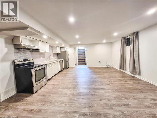 Open-concept living space featuring wood-finish flooring, a full kitchen with stainless steel appliances, recessed lighting, and a neutral color palette - 11 Duncairn Avenue, Kitchener, ON 