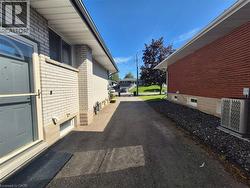 Paved driveway separating two brick properties, featuring light-colored brick with white trim on one side and red brick with white trim on the other - 