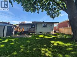 Spacious backyard featuring a large green lawn, multi-level wood deck, and a detached storage shed - 