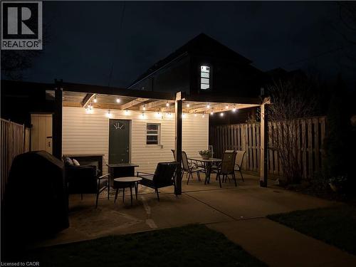 Outdoor patio area featuring a concrete surface, overhead string lighting, and a partial privacy fence - 153 Elgin Street, Hamilton, ON 