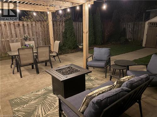 The patio features a pergola with string lights, a fire pit, and a concrete surface - 153 Elgin Street, Hamilton, ON 