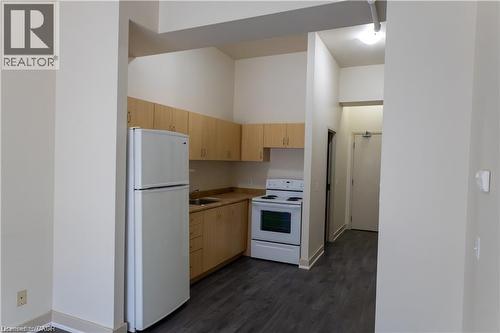 Kitchenette featuring light wood-finish cabinetry, a white refrigerator, a white electric range, and dark wood-finish flooring - 365 Colborne Street, Brantford, ON 
