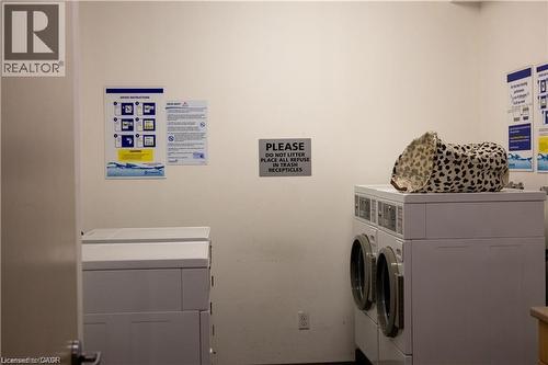 Common area laundry facility with multiple white front-loading washing machines and top-loading dryers - 365 Colborne Street, Brantford, ON 