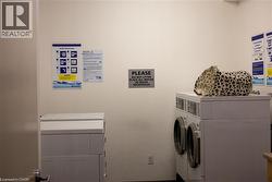 Common area laundry facility with multiple white front-loading washing machines and top-loading dryers - 