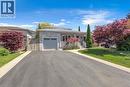 Stone-clad exterior featuring a light gray garage door, a front porch with white railings, and a paved driveway - 640 Acadia Drive, Hamilton, ON 