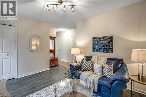 Open-concept living area featuring wood-finish flooring, a track lighting fixture, white trim, and light wall paint - 640 Acadia Drive, Hamilton, ON 