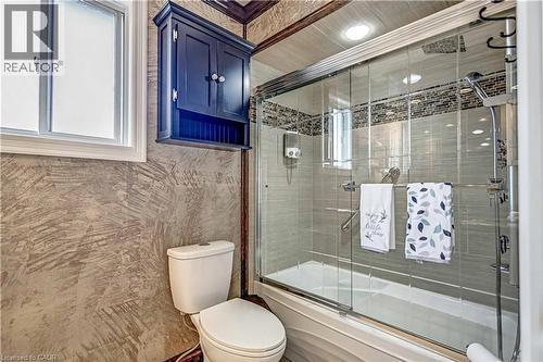 Full bathroom featuring a shower-tub combination with sliding glass enclosure, tile surround with decorative accent band, and recessed lighting - 640 Acadia Drive, Hamilton, ON 