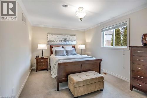 Carpeted bedroom featuring a window, ceiling light fixture, crown molding, baseboards, and a wall vent - 640 Acadia Drive, Hamilton, ON 