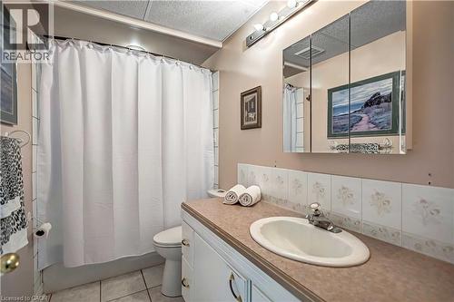 Bathroom featuring a vanity with an integrated sink, a medicine cabinet, a full bathtub with shower, and tiled flooring - 640 Acadia Drive, Hamilton, ON 