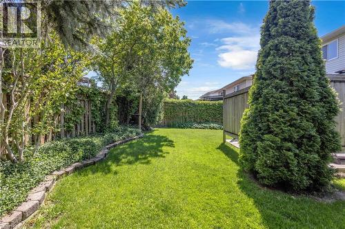Expansive lawn area bordered by a wood fence with lush green foliage - 640 Acadia Drive, Hamilton, ON 