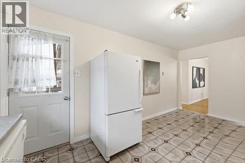 Kitchen area featuring patterned floor tiling, a white paneled door with window, and a three-bulb ceiling light fixture - 957 Stone Church Road E, Hamilton, ON - Indoor Photo Showing Other Room