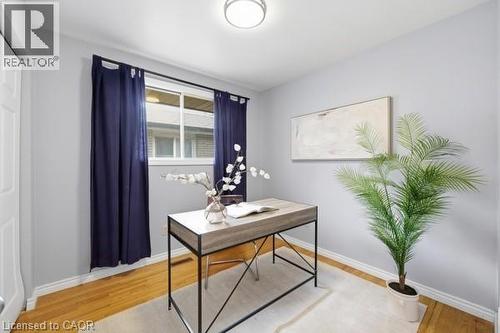 Bright room featuring a window with dark blue curtains, wood-finish flooring, a contemporary flush-mount ceiling light, and light gray walls with white baseboards - 957 Stone Church Road E, Hamilton, ON - Indoor Photo Showing Office