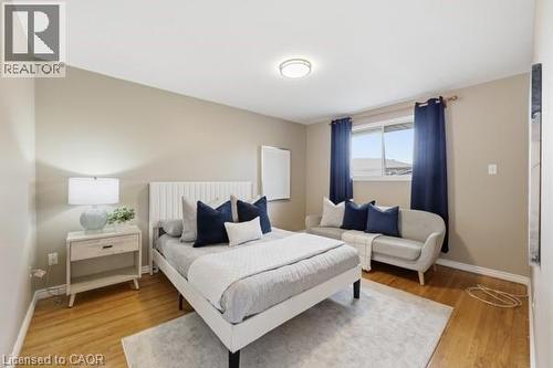 Spacious room featuring wood-finish flooring, a contemporary ceiling light fixture, and a window with dark curtains - 957 Stone Church Road E, Hamilton, ON - Indoor Photo Showing Bedroom