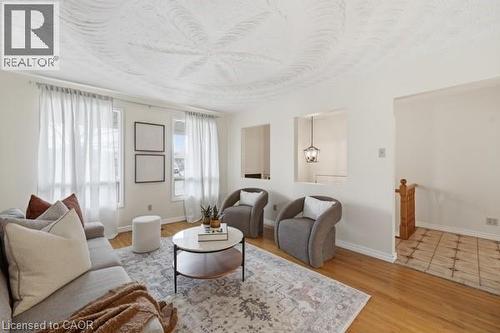 Living area featuring light wood-finish flooring, multiple windows with sheers, and a textured ceiling - 957 Stone Church Road E, Hamilton, ON - Indoor Photo Showing Living Room