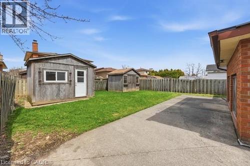 Spacious backyard featuring a substantial paved area, a manicured lawn, and two integrated storage sheds - 957 Stone Church Road E, Hamilton, ON - Outdoor