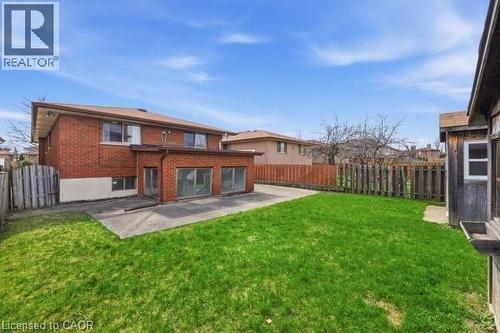 Spacious rear yard featuring an expansive lawn, concrete patio, and mature perimeter fencing - 957 Stone Church Road E, Hamilton, ON - Outdoor