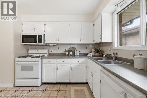 Kitchen featuring white cabinetry, a built-in microwave, gas range, double basin stainless steel sink, and a white dishwasher - 957 Stone Church Road E, Hamilton, ON - Indoor Photo Showing Kitchen With Double Sink