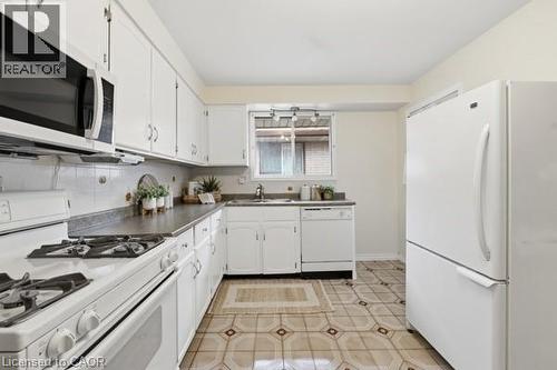 Kitchen featuring white cabinetry, grey countertops, white appliances, and patterned floor tiles - 957 Stone Church Road E, Hamilton, ON - Indoor Photo Showing Kitchen