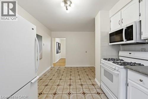 Kitchen featuring patterned tile flooring, white cabinetry, and white appliances including a refrigerator, gas range, and over-the-range microwave - 957 Stone Church Road E, Hamilton, ON - Indoor Photo Showing Kitchen