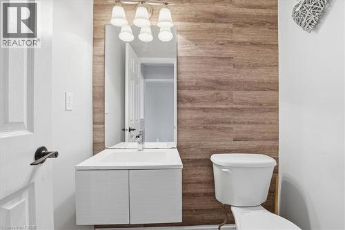 Bathroom featuring a floating vanity with an integrated sink, wood-finish accent wall, wall-mounted mirror, and vanity light fixture - 136 Carpenter Road, Cambridge, ON - Indoor Photo Showing Living Room