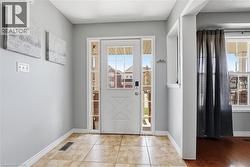 Entryway featuring a white door with glass lites, sidelight windows, and tile flooring - 