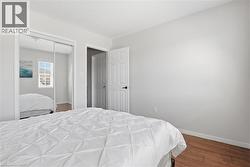 Bedroom featuring wood-finish flooring, a full-lite interior door, and a mirrored closet with sliding doors - 