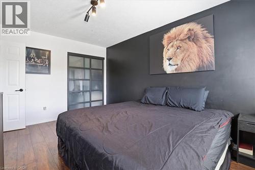 Spacious room featuring wood-finish flooring, a contemporary ceiling light fixture, and a dark accent wall - 136 Carpenter Road, Cambridge, ON - Indoor Photo Showing Bedroom