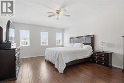 Spacious room featuring wood-finish flooring, three windows with blinds, a ceiling fan with integrated lighting, and light-toned walls - 